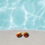 Sunglasses sit by a pool.
