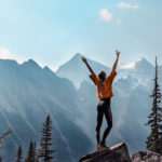 A woman celebrates reaching the pinnacle of a mountain.