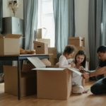 A happy diverse family sits in their living room amongst cardboard boxes.