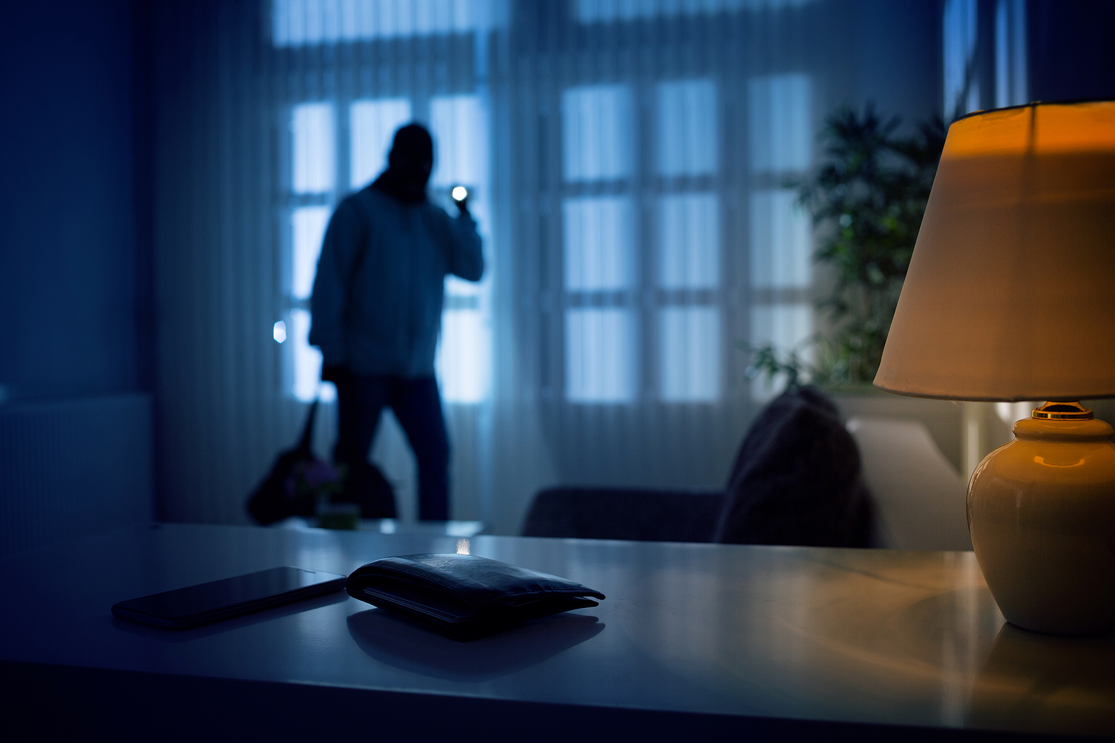 Burglar or intruder inside of a house or office with flashlight.