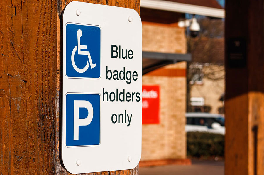 Photo of a sign with the blue handicapped symbol and blue parking symbol with the text blue badge holders only.