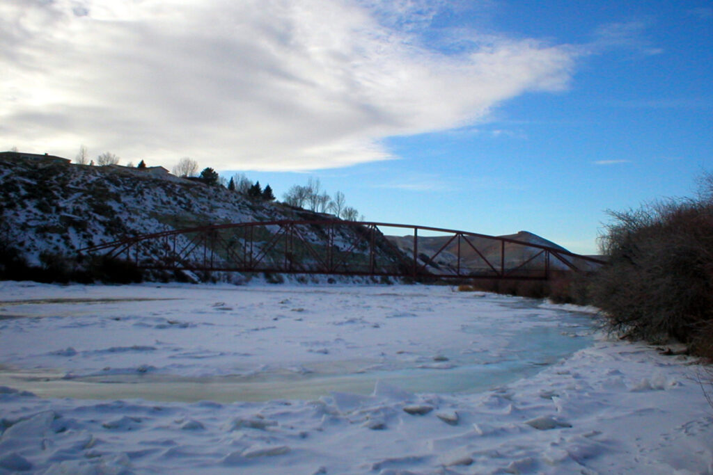 Frozen river and steel bridge at Expedition Island in winter, located in Green River, Wyoming.